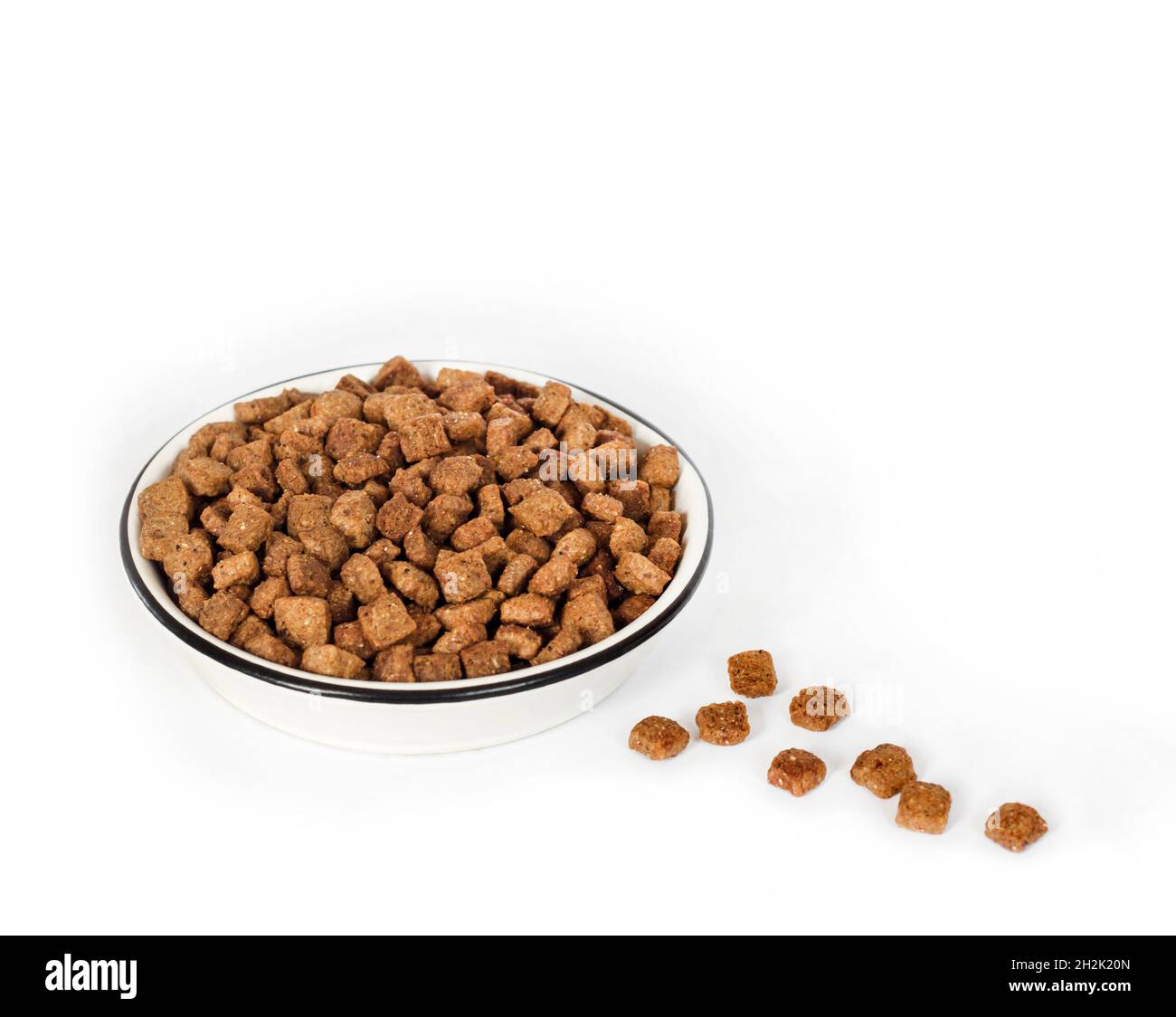 Asciugare gli alimenti per animali domestici in un recipiente in ceramica bianca isolato su sfondo bianco. Spazio di copia Foto Stock