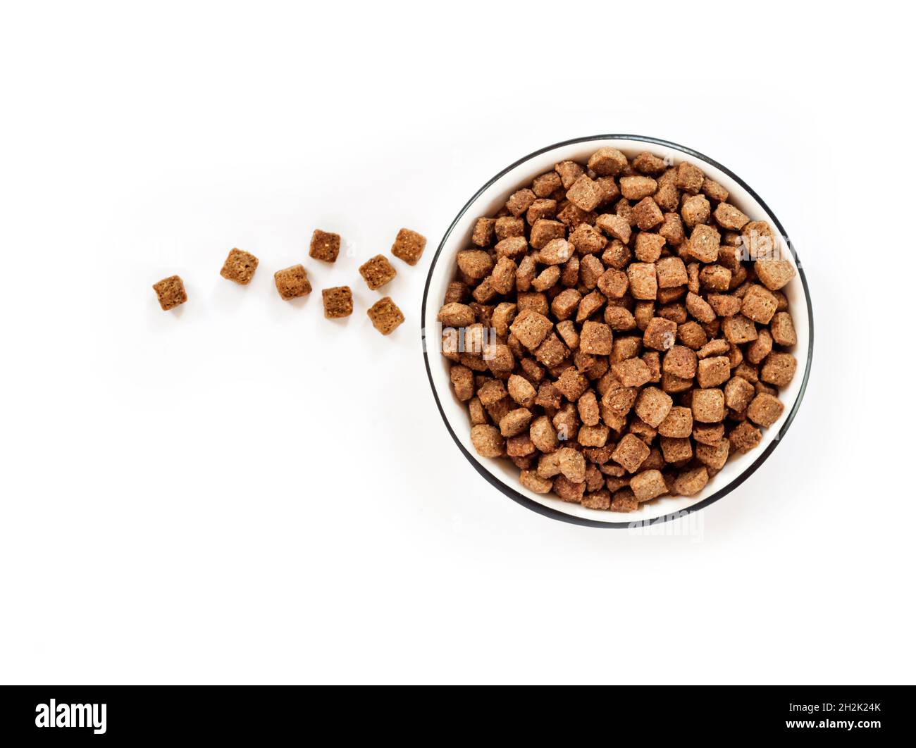 Asciugare gli alimenti per animali domestici in un recipiente in ceramica bianca isolato su sfondo bianco. Disposizione piatta, vista dall'alto. Spazio di copia Foto Stock