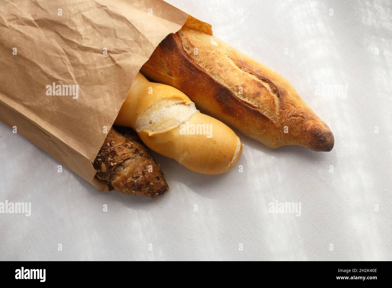 segale, grano, baguette multigrain in sacchetto di carta su tovaglia bianca Foto Stock