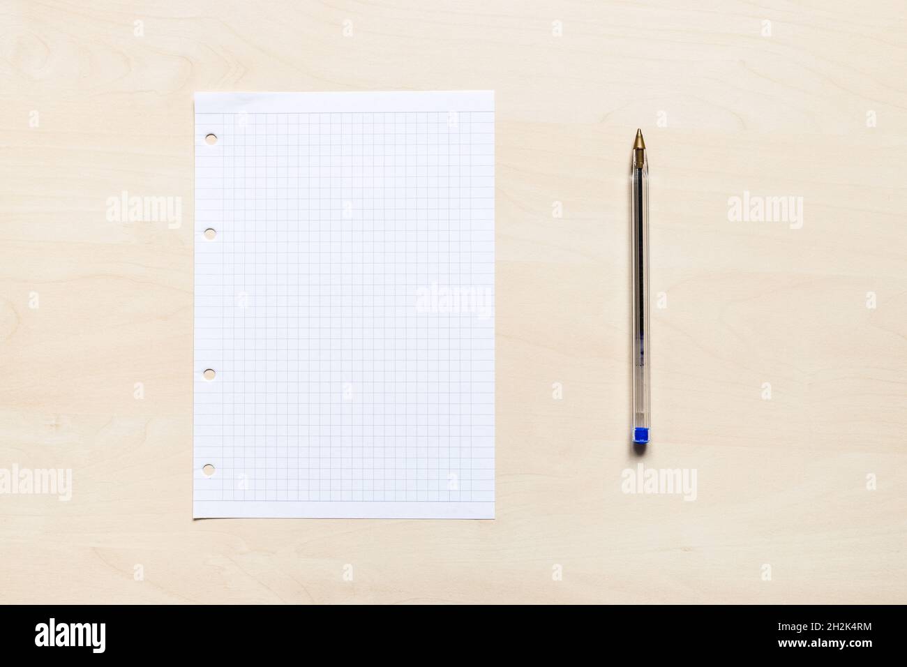 vista dall'alto della penna di plastica e del foglio bianco di carta squadrata su asse di legno marrone chiaro Foto Stock