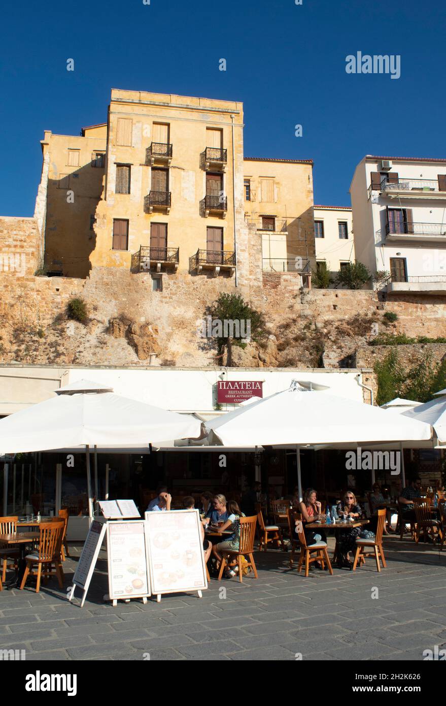 Il bellissimo porto storico di Chania, Creta, i caffè e le taverne sul marciapiede della Grecia, vicino alla splendida spiaggia verticale con spazio copia Foto Stock