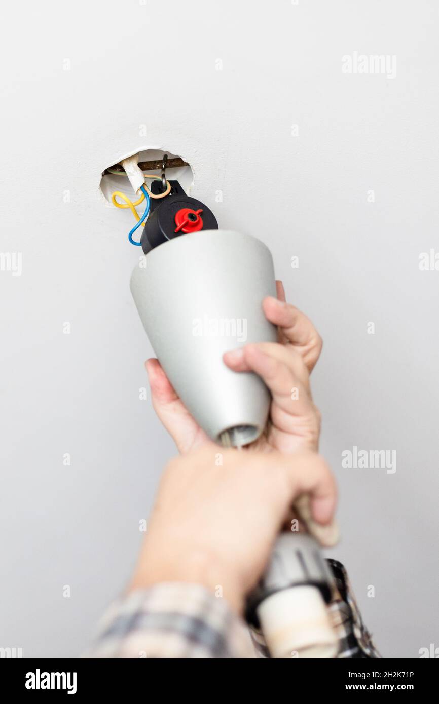 l'uomo installa il cappuccio decorativo della lampada da soffitto a casa Foto Stock