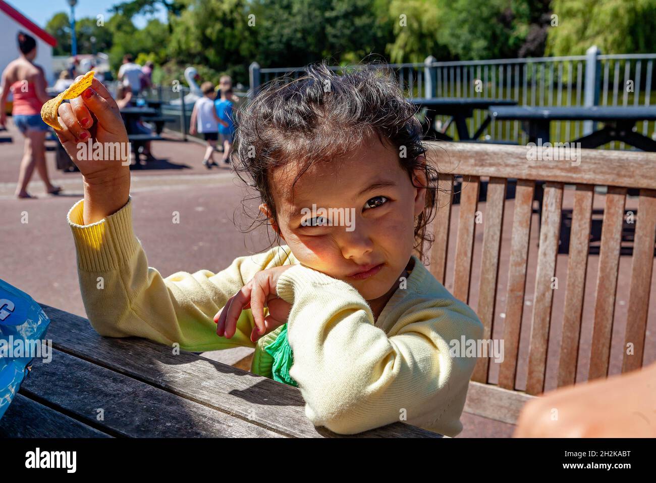 La giovane ragazza inglese/tailandese siede a una panchina che tiene una Tortilla al campo di vacanze di Pwllheli Foto Stock