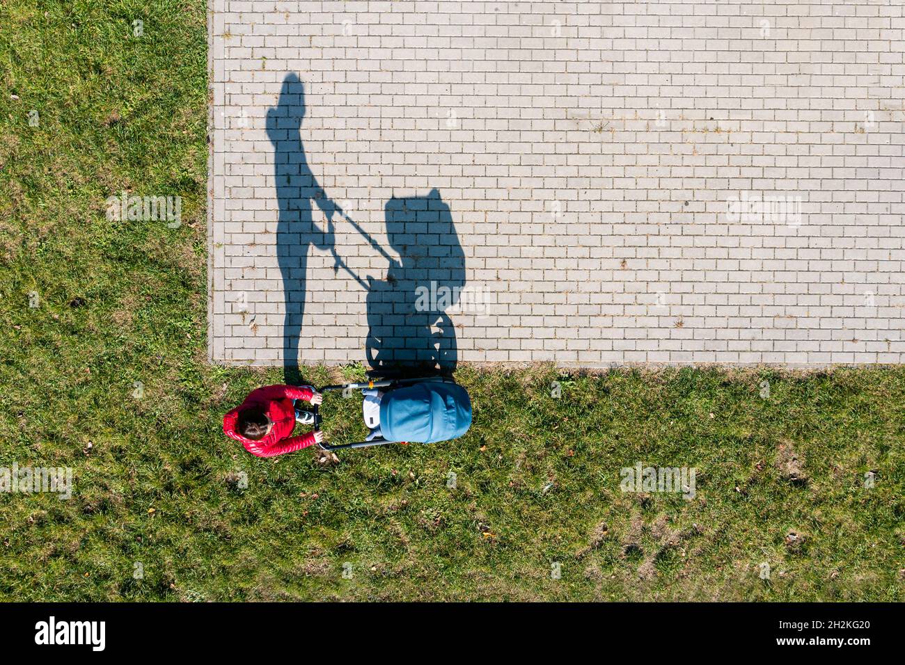 Vista aerea del genitore con un passeggino in una passeggiata durante la giornata di sole, prospettiva direttamente sopra Foto Stock