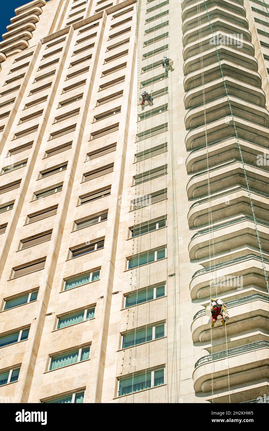 Arrampicatori riparano la facciata in marmo bianco di un grattacielo Foto Stock