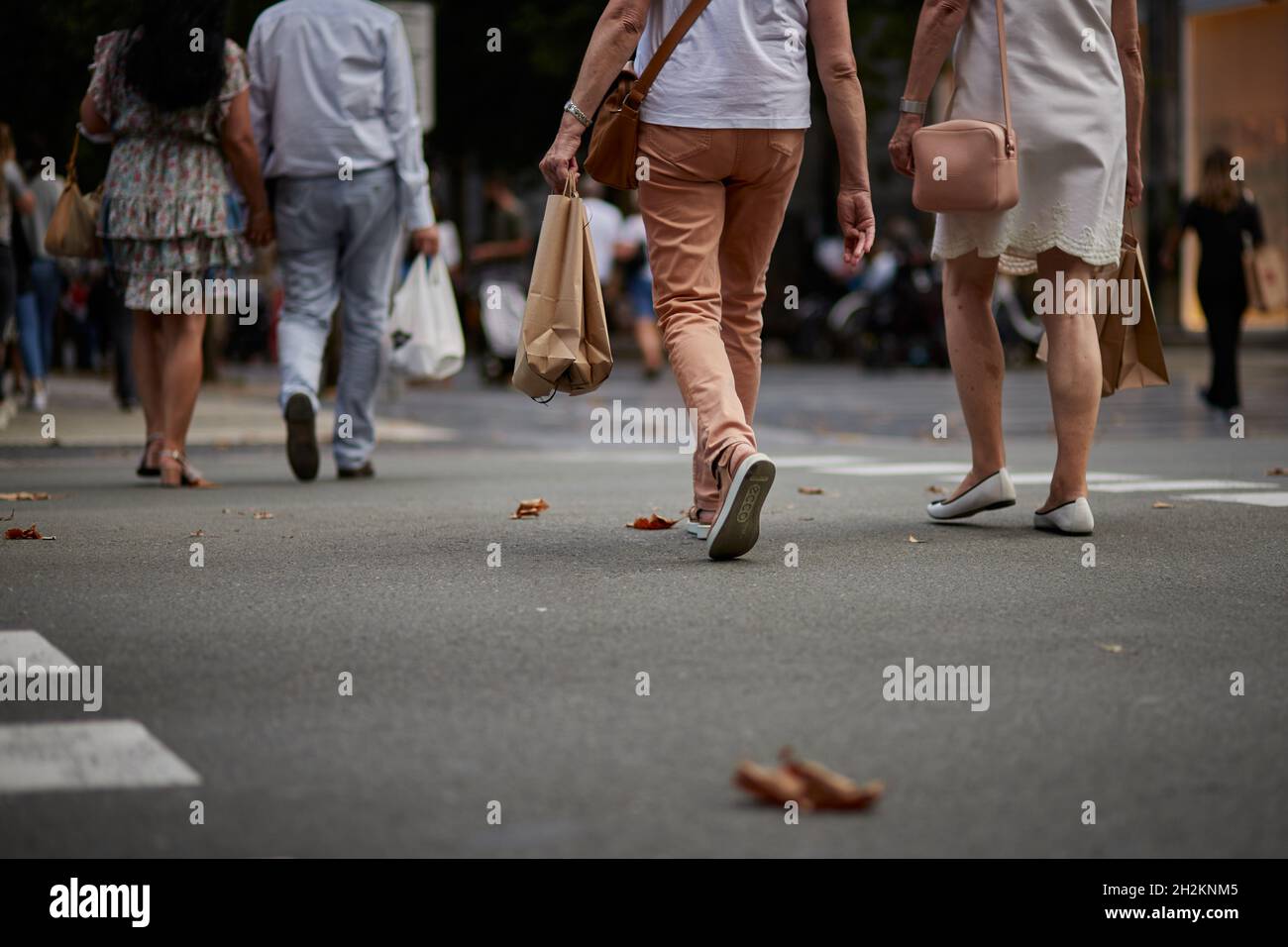 Donna che attraversa una strada con alcuni sacchetti shopping. Foto Stock
