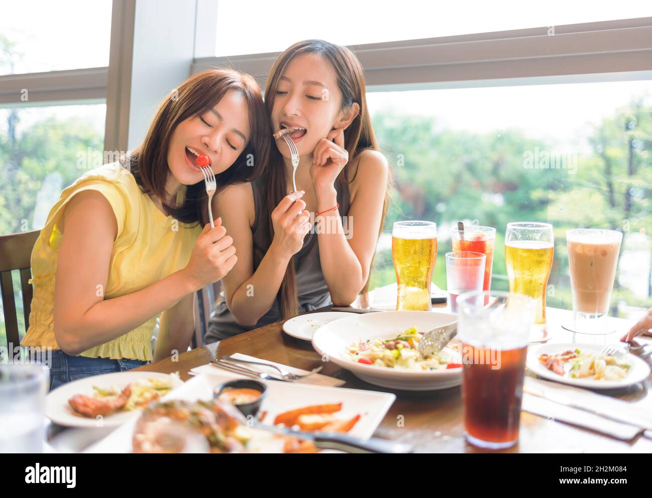 Buone amiche gustando cibo e bevande al ristorante Foto Stock