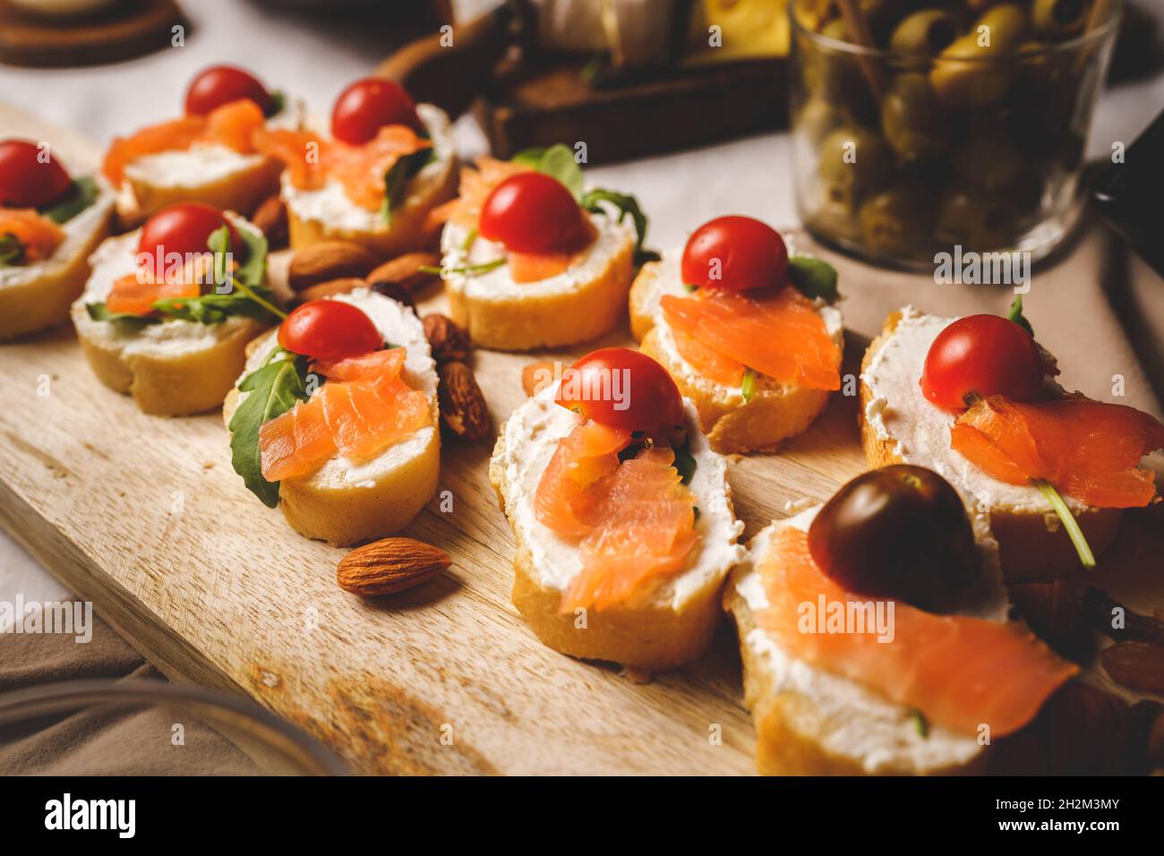 salmoni affumicati stagionati secchi sulle fette di pane e sandwich di formaggio spalmabile con pomodori ciliegini e insalata di rucola Foto Stock