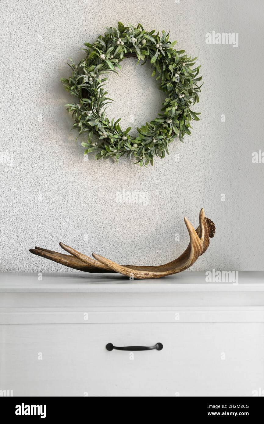 Corno di cervo sul ripiano e corona di vischio appesi sulla parete di luce  Foto stock - Alamy