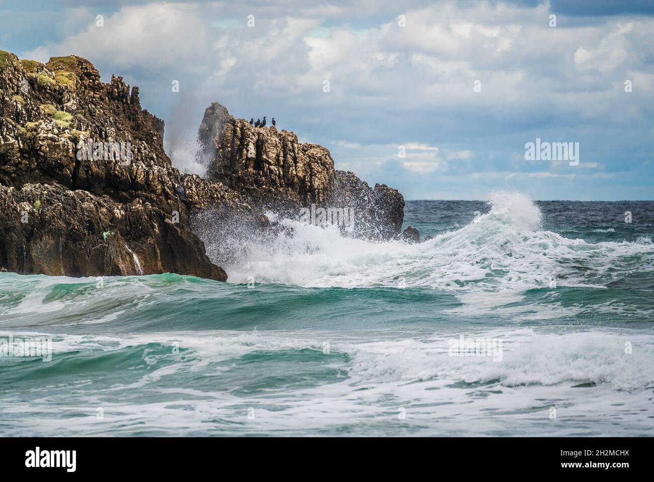 Scogliere frastagliate e mare vorticoso. Frastagliata costa rocciosa con acqua bianca che rotola intorno alle rocce Foto Stock