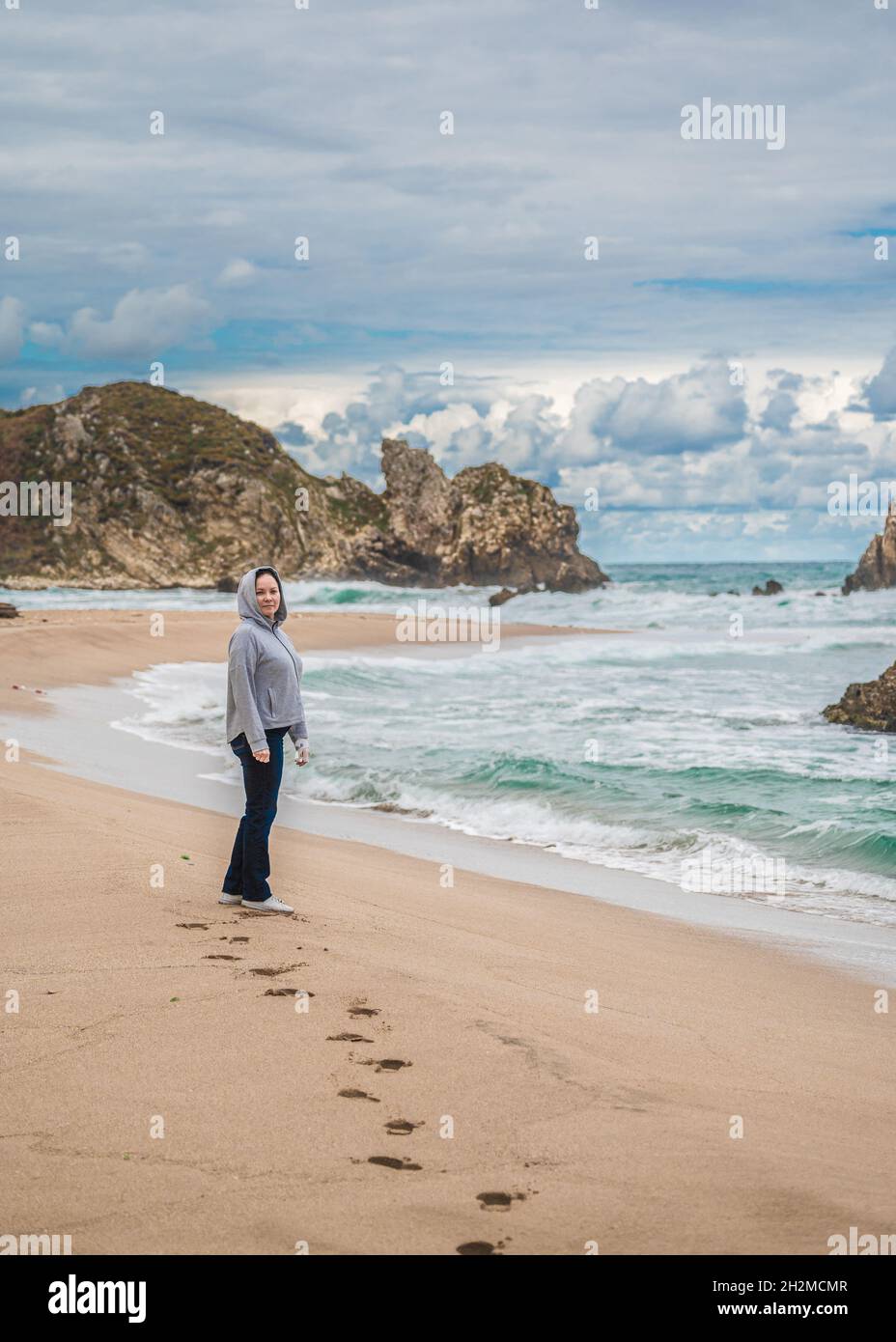 donna di mezza età cammina lungo la linea dell'oceano in autunno, inverno, stile di vita attivo. camminando lungo il mare in clima fresco. costa della california Foto Stock