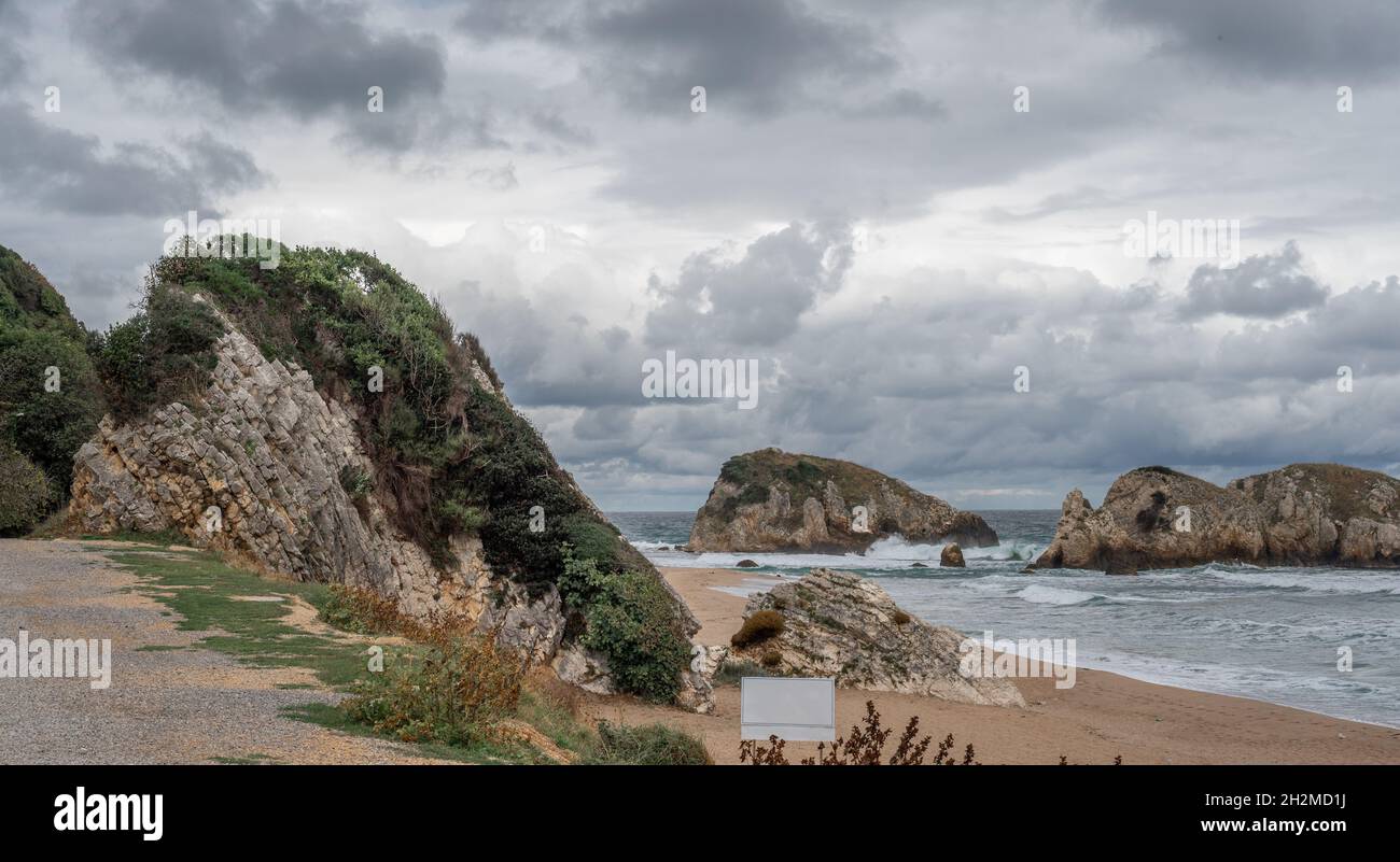 Acqua dell'oceano spruzzi sulla roccia Peacock spiaggia Turchia con il cielo e le nuvole belle. Onda di mare che si tuffa in pietra a riva del mare in inverno. Costa rocciosa wit Foto Stock