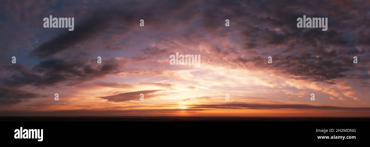 Cielo spettacolare al tramonto o all'alba. Nuvole mistiche scure. Luce del sole in nuvole di arancio sfocate Foto Stock