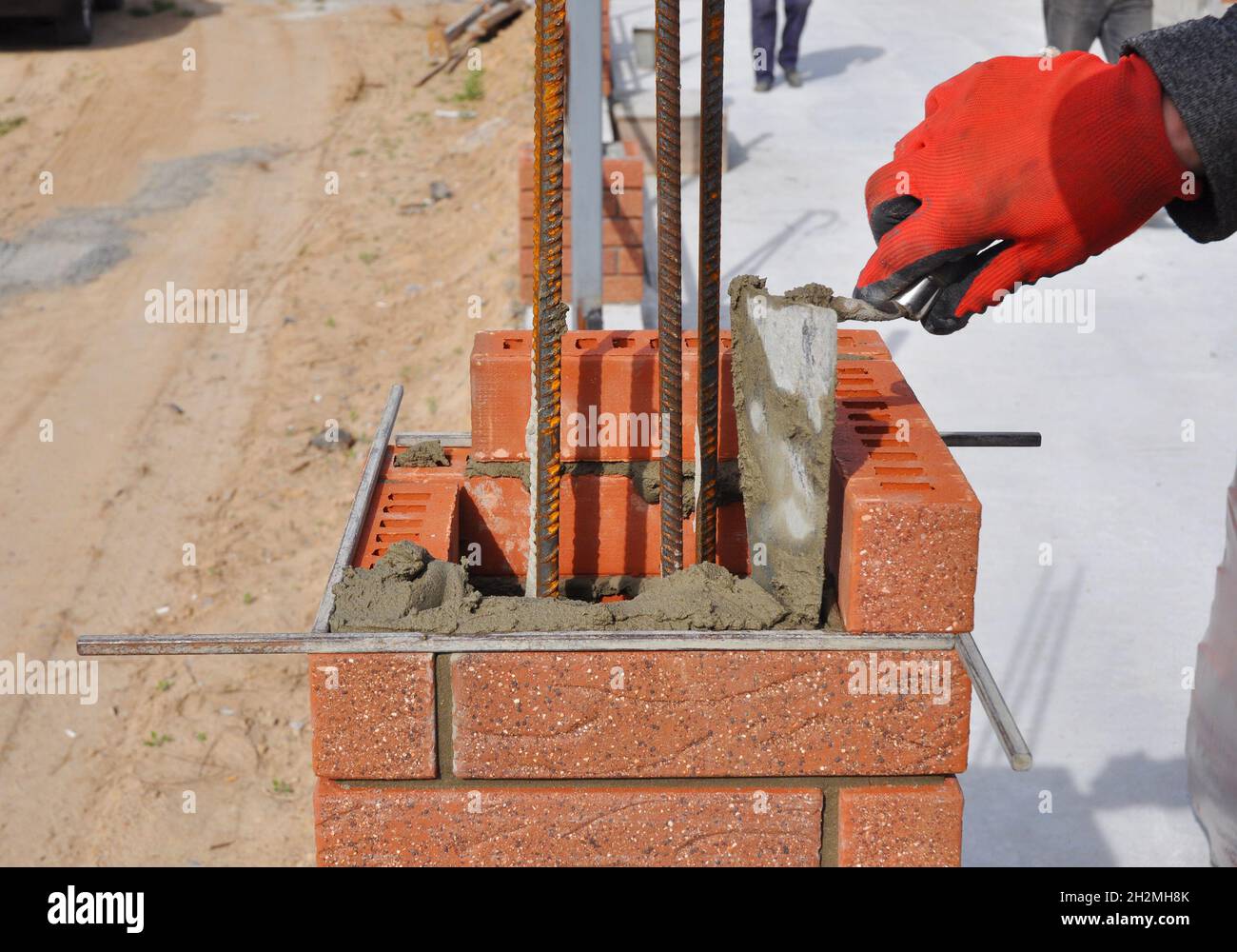 Primo piano di un lavoratore in muratura Installazione di blocchi rossi e cianfrinatura giunti in muratura in muratura in mattoni parete esterna con coltello per putty con cazzuola all'aperto. Muratura. Foto Stock