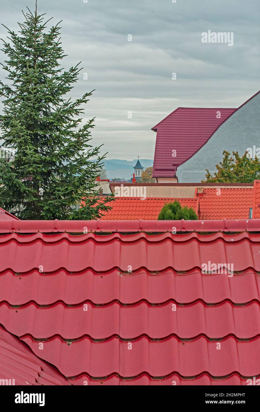 tetti della città che portano ad una chiesa in lontananza, e un abeto Foto Stock