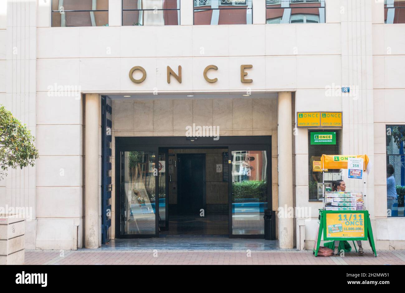 Una donna vende i biglietti della lotteria di fronte a Once, Organizzazione della gente cieca spagnola edificio a Malaga, Andalusia, Spagna. Foto Stock