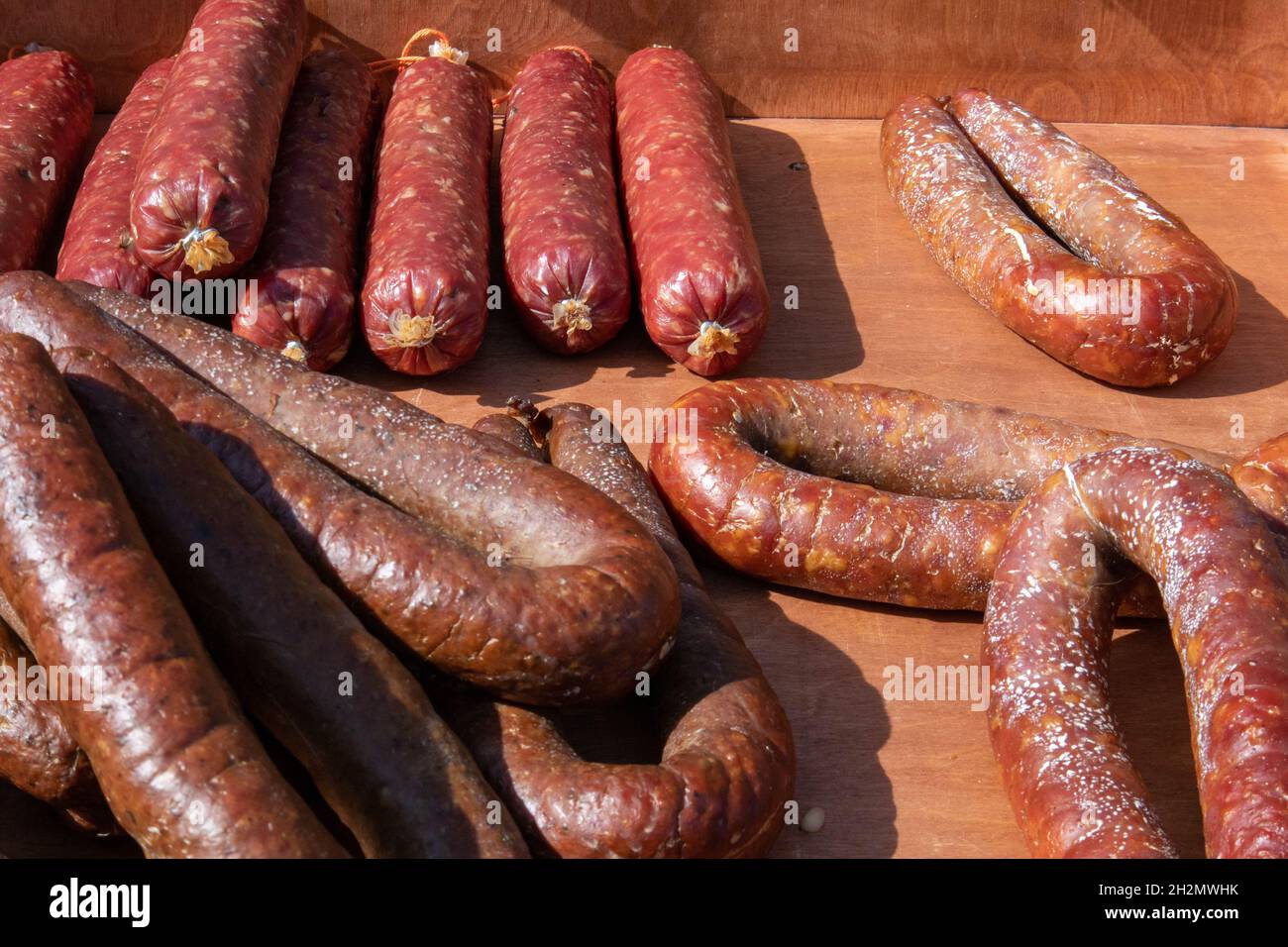 Pochi appetitosi salsicce rustiche fatte in casa che giacciono alla tenda del commercio equo e solidale del villaggio Foto Stock