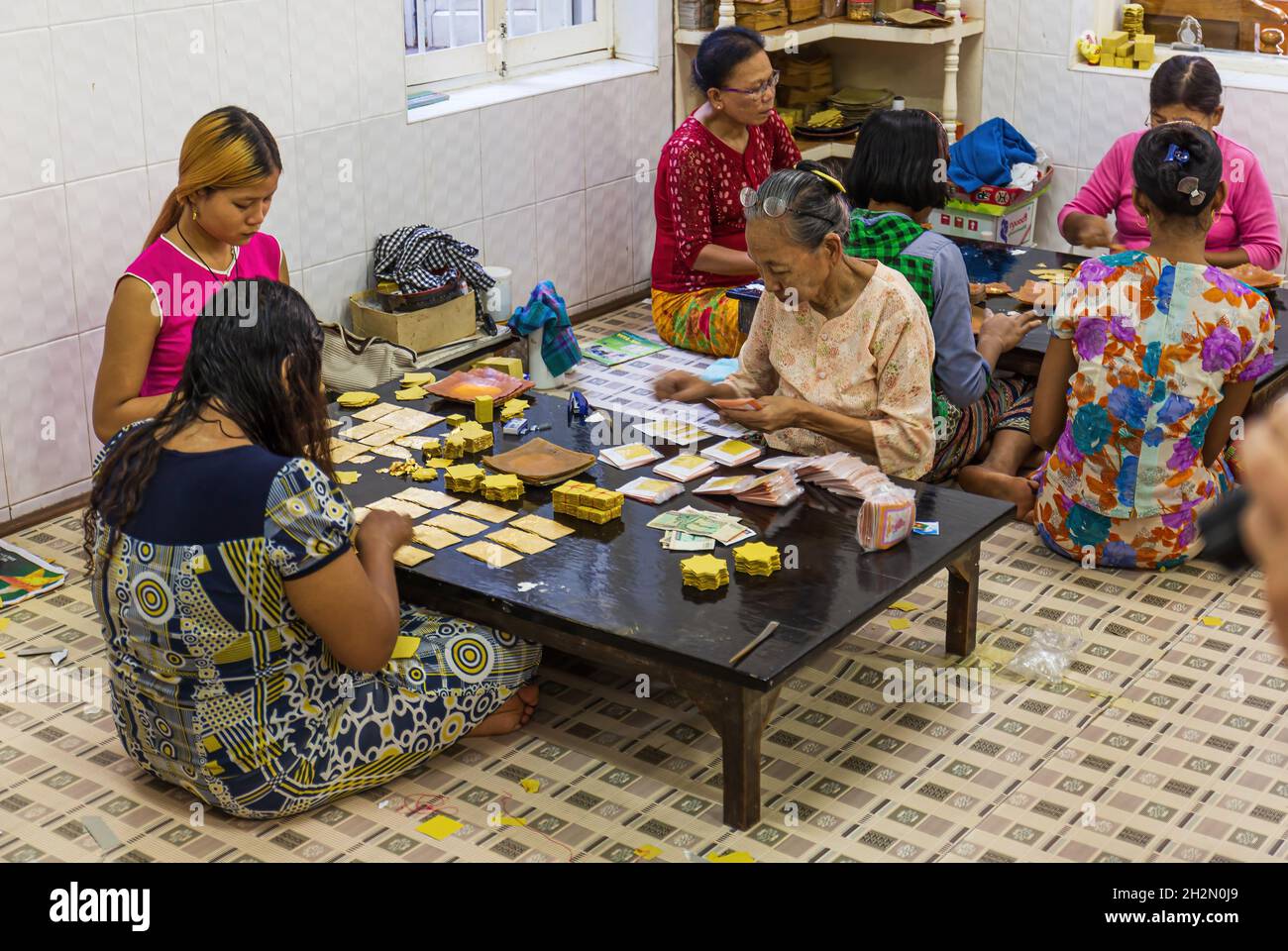 MANDALAY, MYANMAR - DICEMBRE 30: Le donne controllano i fogli della foglia d'oro ad una fabbrica del fondatore d'oro il 30 dicembre 2016 nella città di Mandalay in Foto Stock
