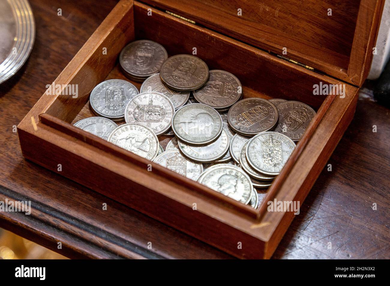 Una moneta di scellino in una scatola di legno in un negozio di antiquariato (Hampton Court Emporium, East Molesay, Regno Unito) Foto Stock