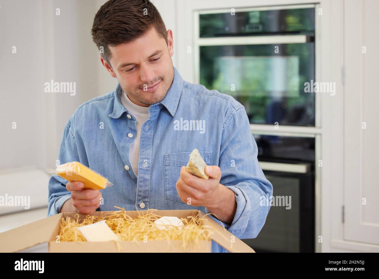 Man Unpacking Online Formaggi di lusso consegnati a casa Foto Stock