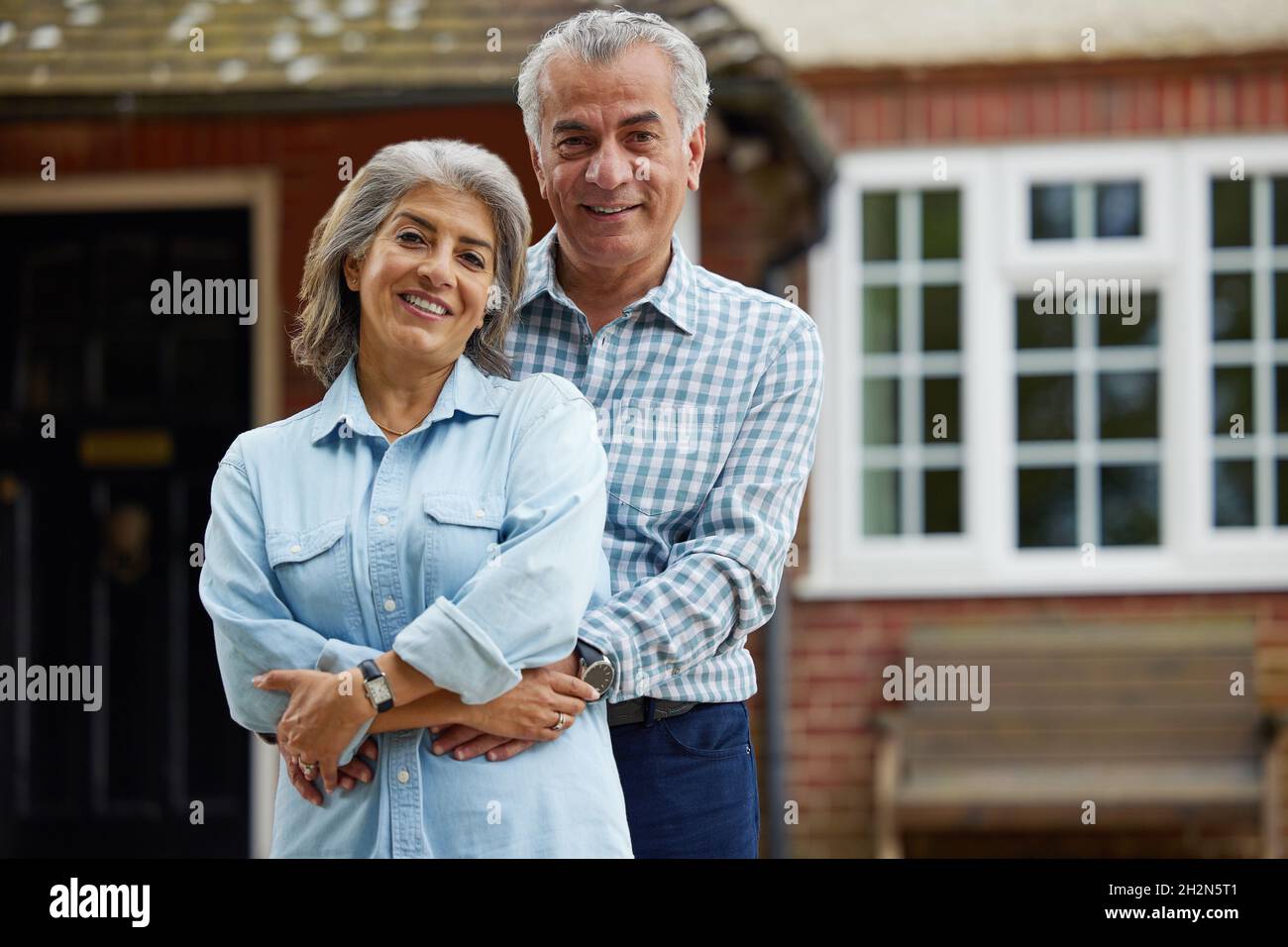 Ritratto di Coppia Matura in piedi nel giardino davanti a casa da sogno in campagna Foto Stock