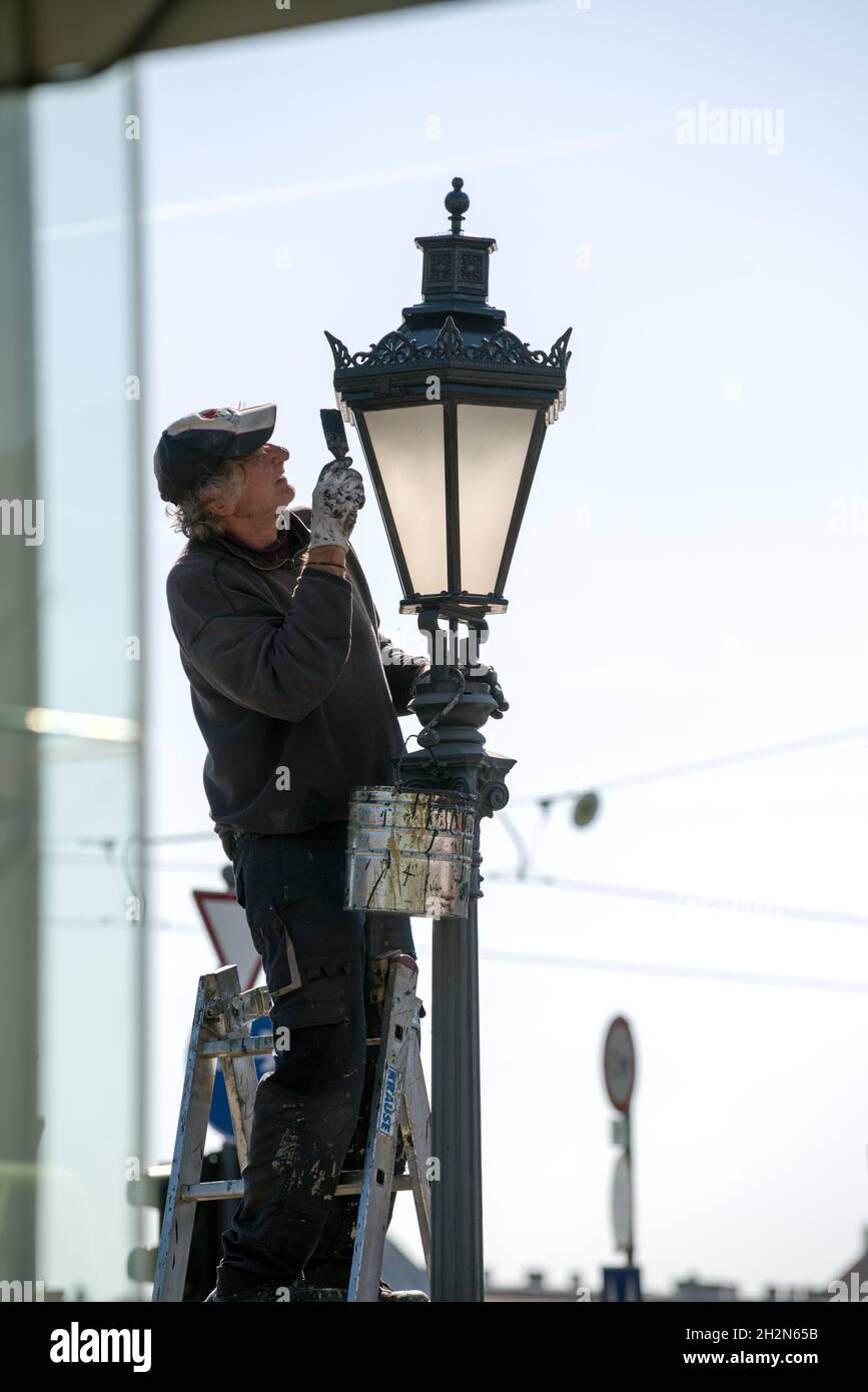 Lavoratore che dipinge una luce stradale Foto Stock