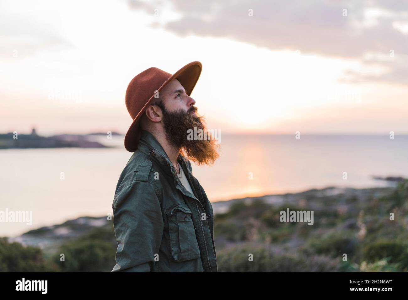 Uomo con barba lunga e cappello durante il tramonto Foto Stock