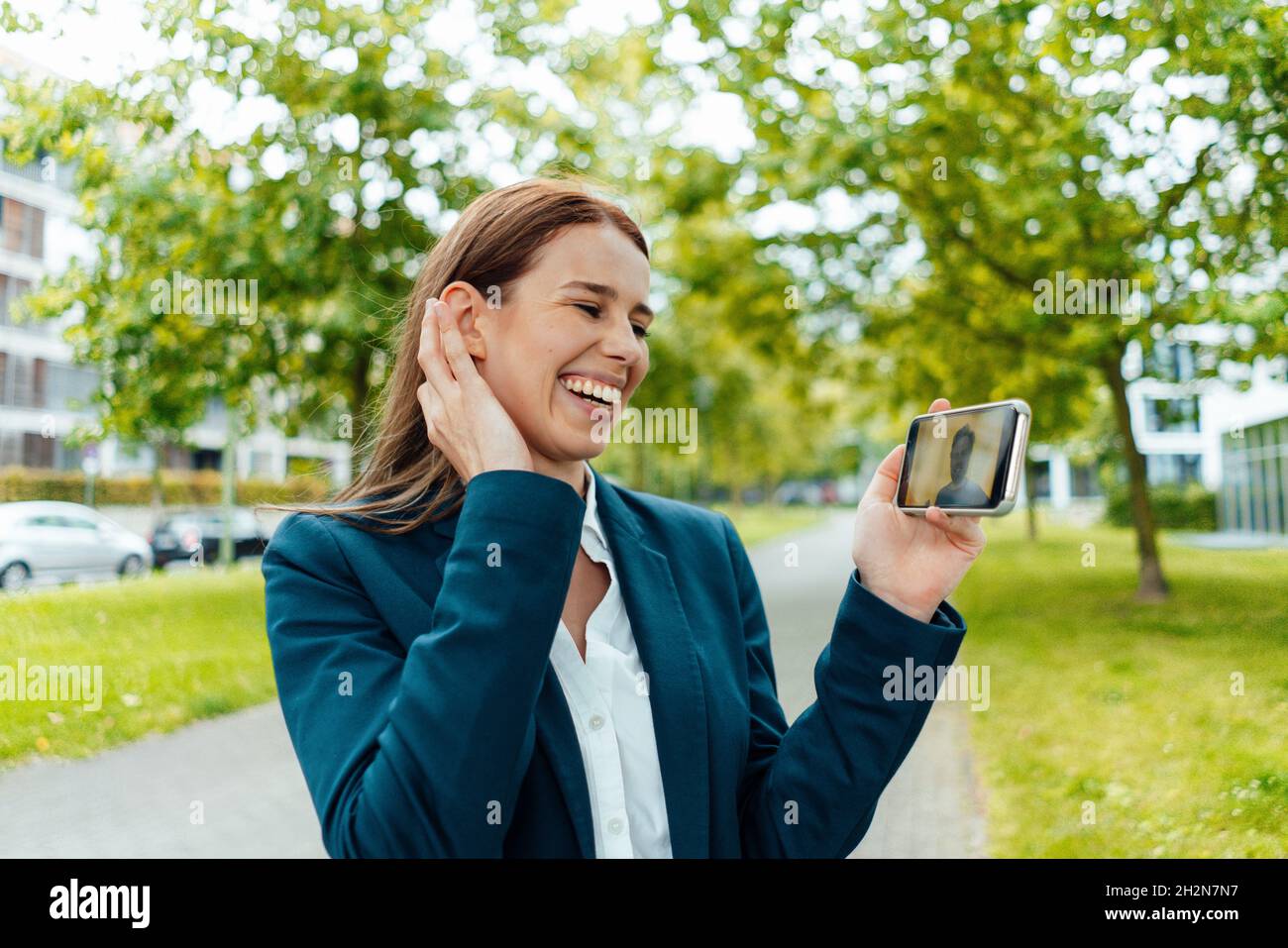 Una ragazza libera sorridente che invia messaggi vocali tramite smartphone al parco Foto Stock