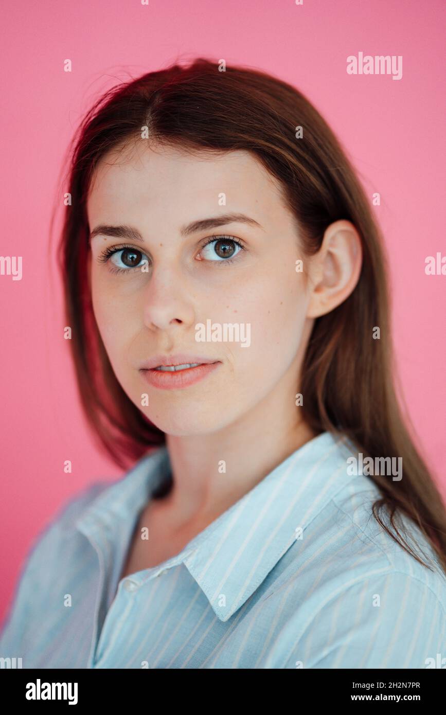 Bella donna con capelli marroni su sfondo rosa Foto Stock