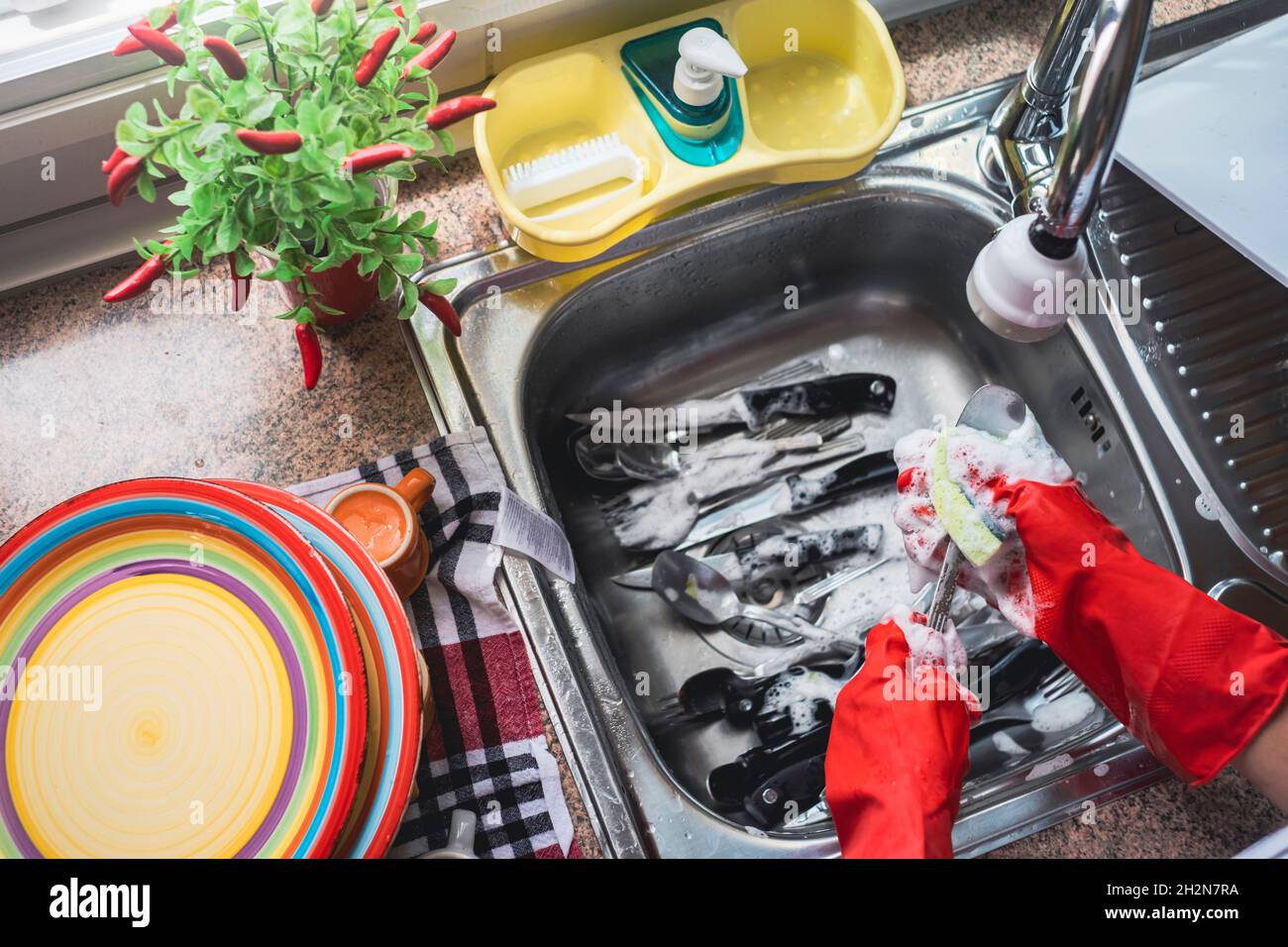 Donna pulizia utensili da cucina a casa Foto Stock