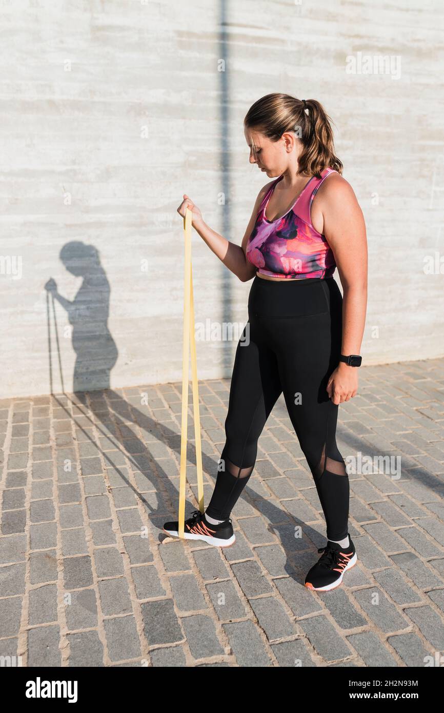 Giovane atleta femminile con banda di resistenza che pratica durante la giornata di sole Foto Stock