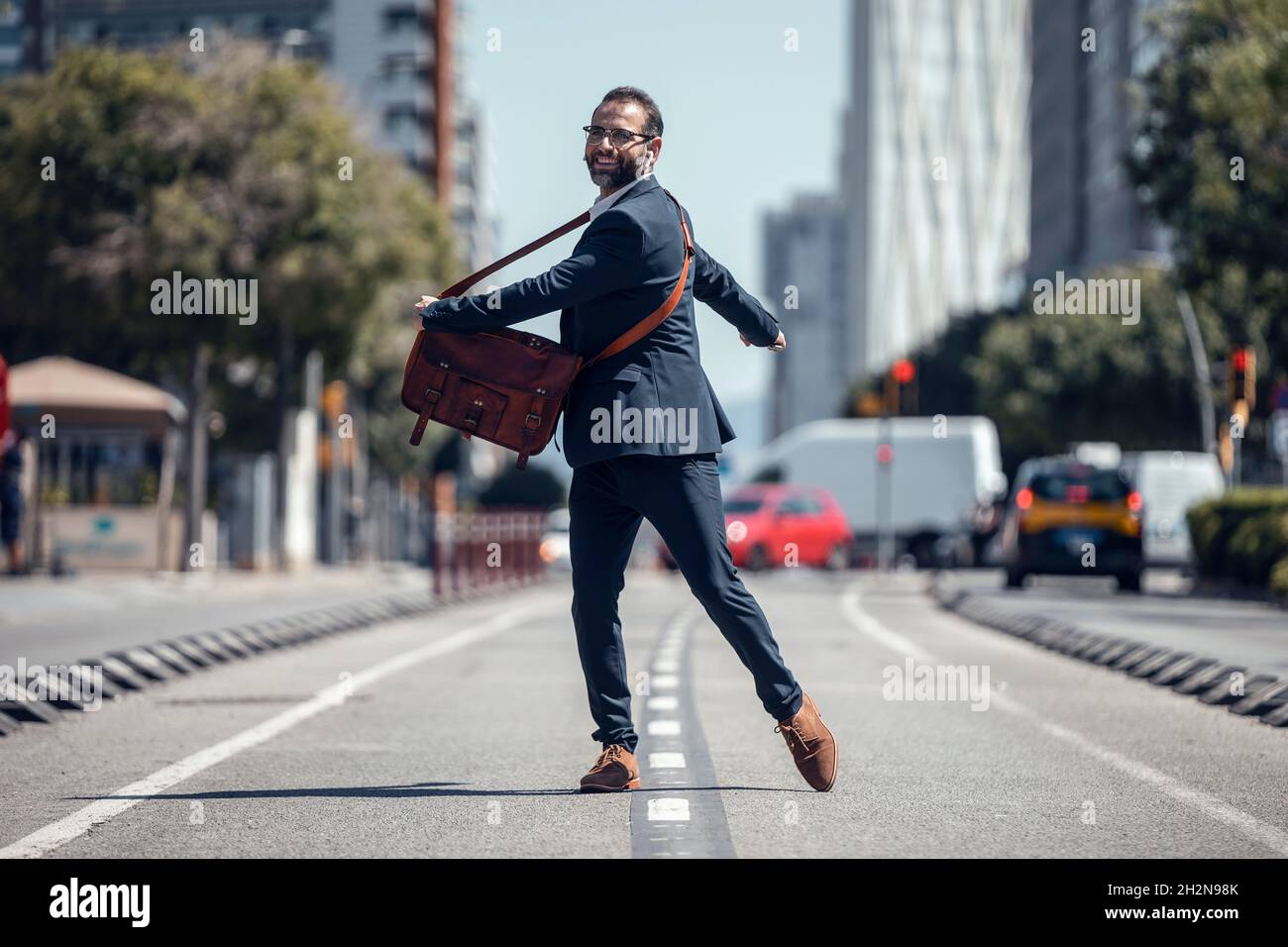 Felice uomo d'affari con borsa a tracolla che gira su strada Foto Stock