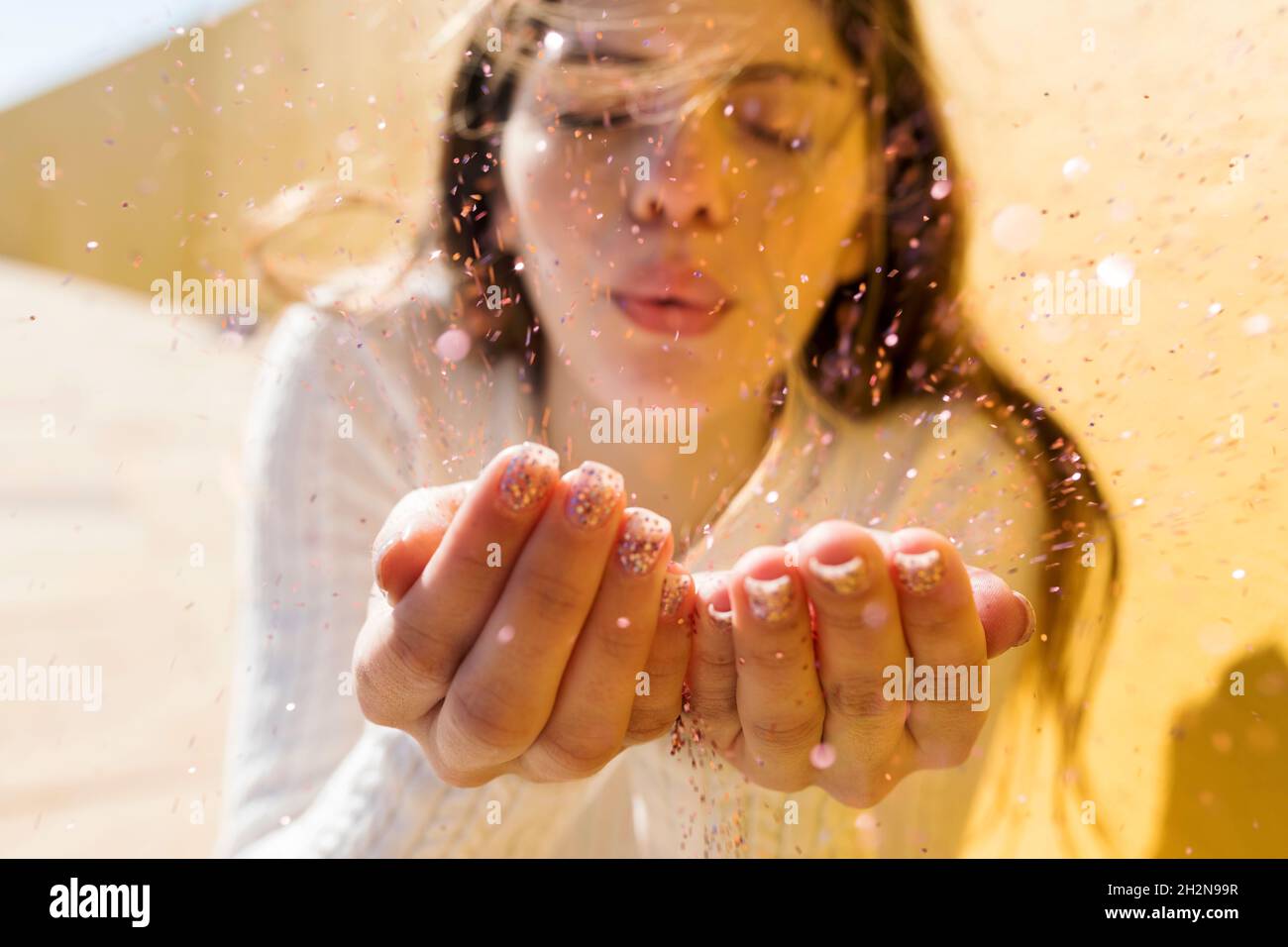 Donna che soffia brillantini durante la giornata di sole Foto Stock