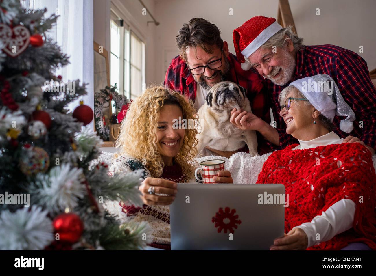 Famiglia con cane che partecipa alla videochiamata attraverso il portatile a casa Foto Stock