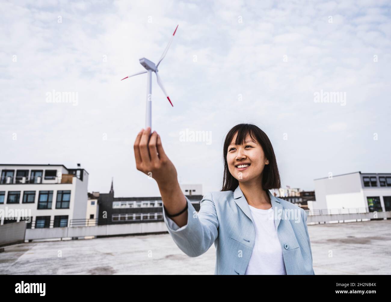 Persona d'affari femminile con modello di turbina eolica sul tetto Foto Stock