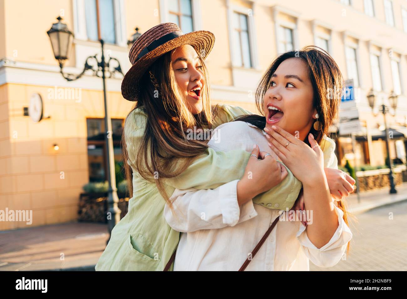 Donna sorpresa guardando un amico abbracciando da dietro in città Foto Stock