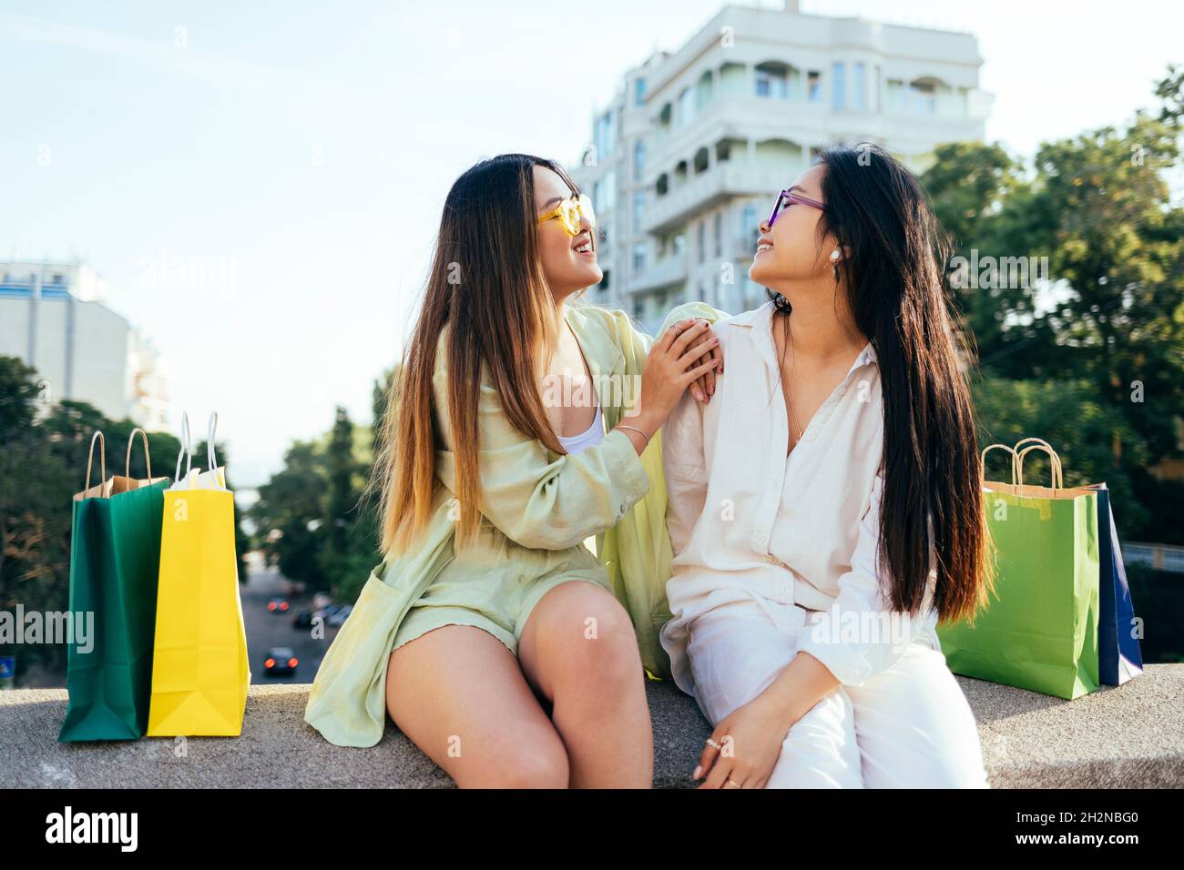 Sorridendo gli amici che si guardano mentre si siedono sulla parete di ritegno Foto Stock