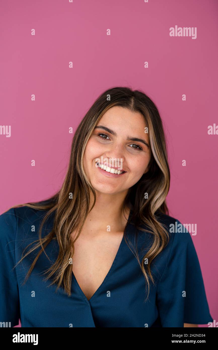 Giovane donna d'affari di fronte al muro di colore rosa Foto Stock