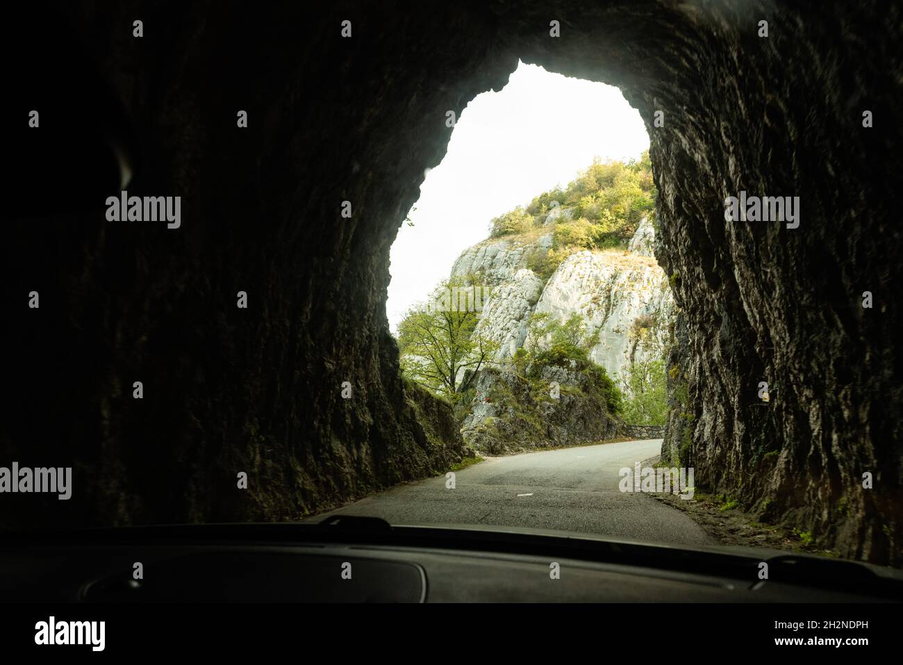 Vista dall'interno di un tunnel roccioso su una strada di montagna dall'auto Foto Stock