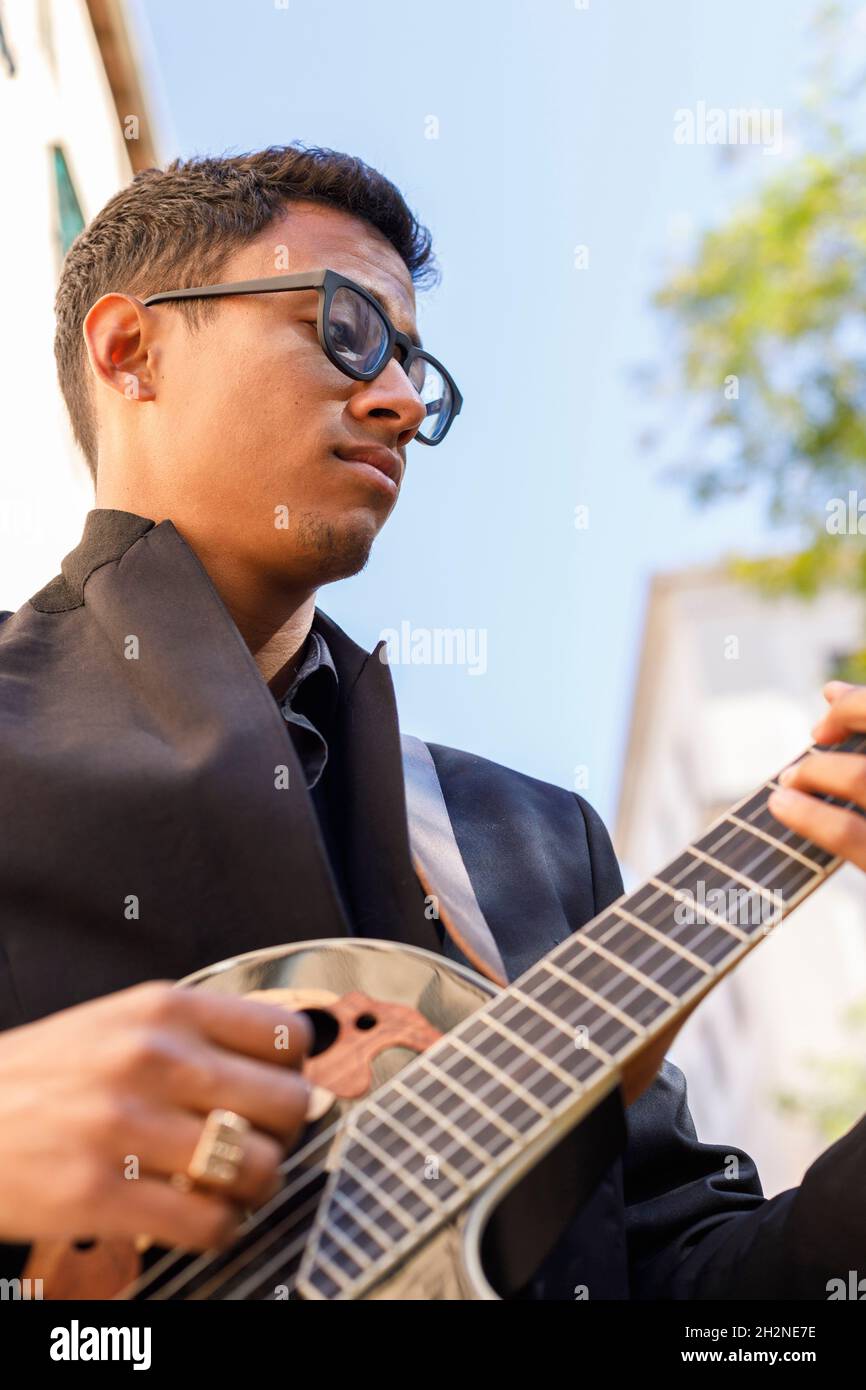 Giovane musicista maschile che suona la chitarra per strada Foto Stock