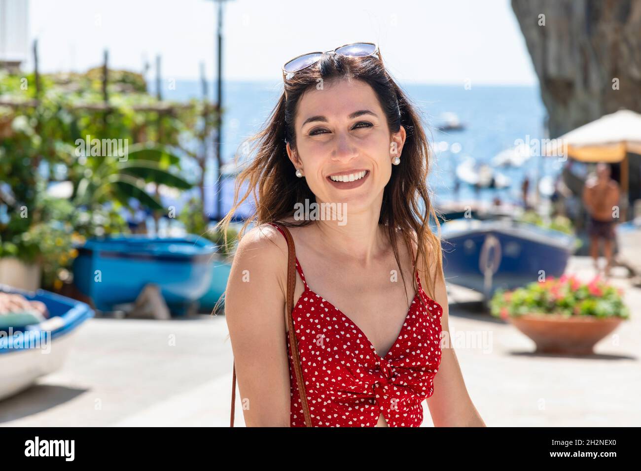 Donna sorridente in abito rosso estivo in spiaggia Foto Stock