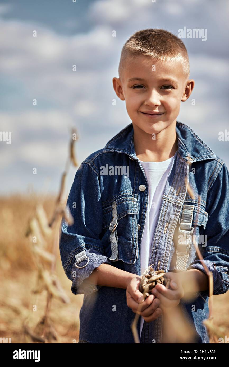 Ragazzo sorridente che tiene la cialda di soia mentre si trova in fattoria durante la giornata di sole Foto Stock