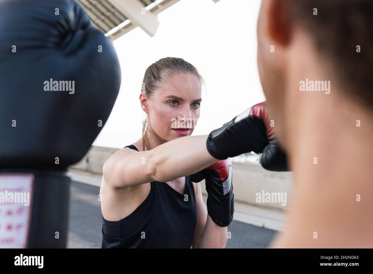 Atleta femminile concentrato che pratica boxe con allenatore maschile Foto Stock