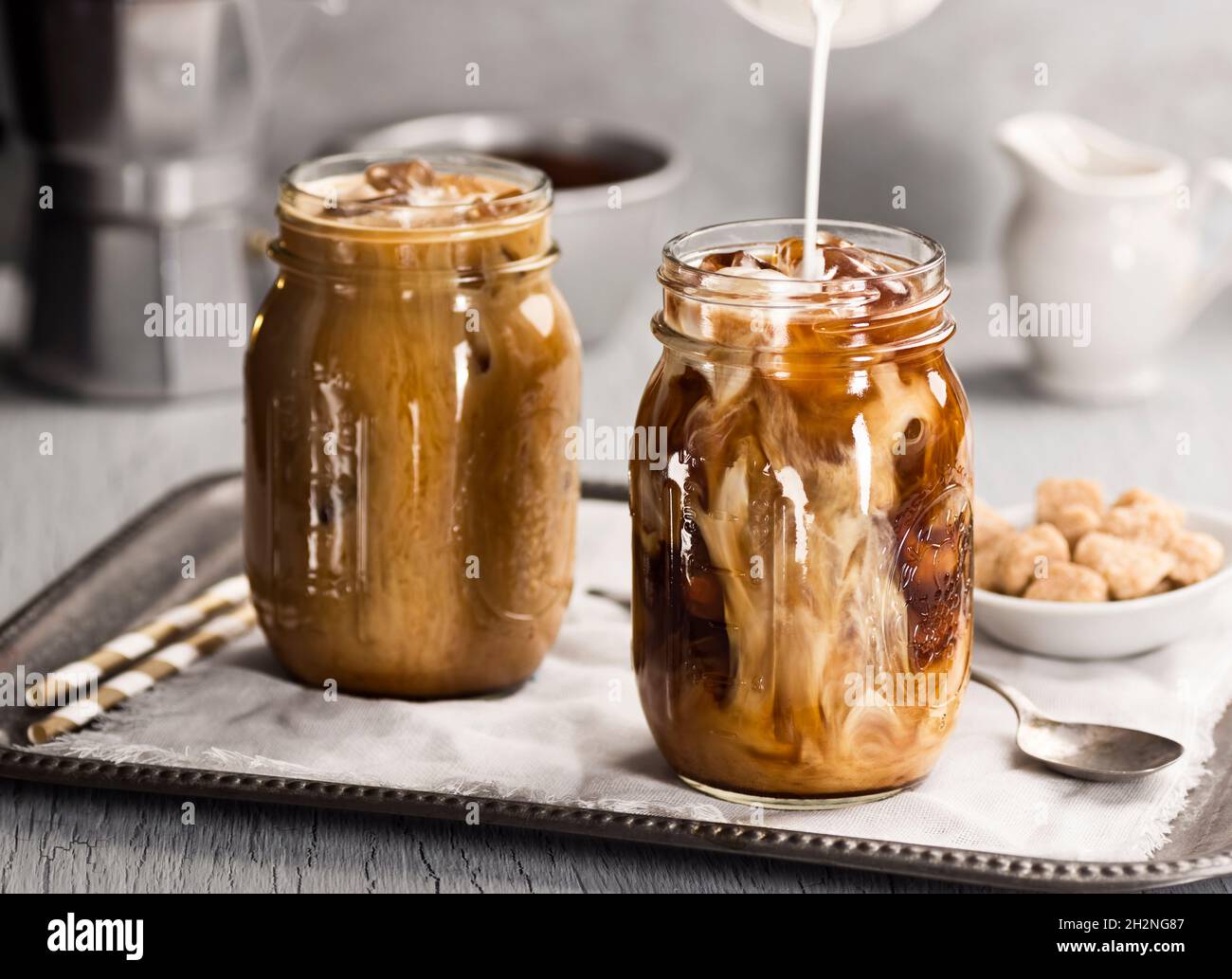 Latte o panna versati in vasetto Mason pieno di caffè freddo o latte freddo con paillette Foto Stock