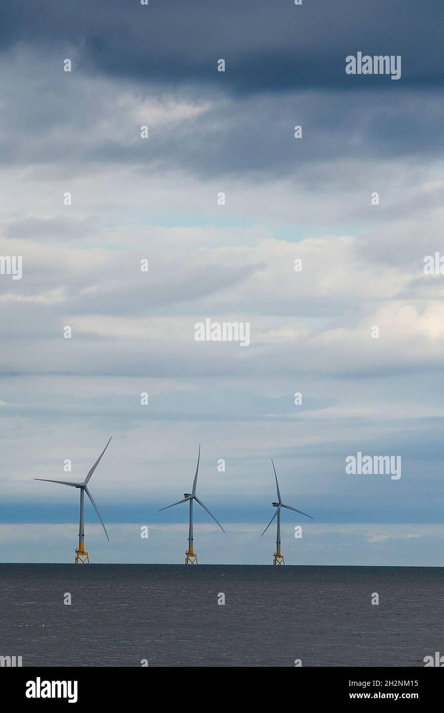 Tre turbine eoliche offshore sotto cielo nuvoloso Foto Stock