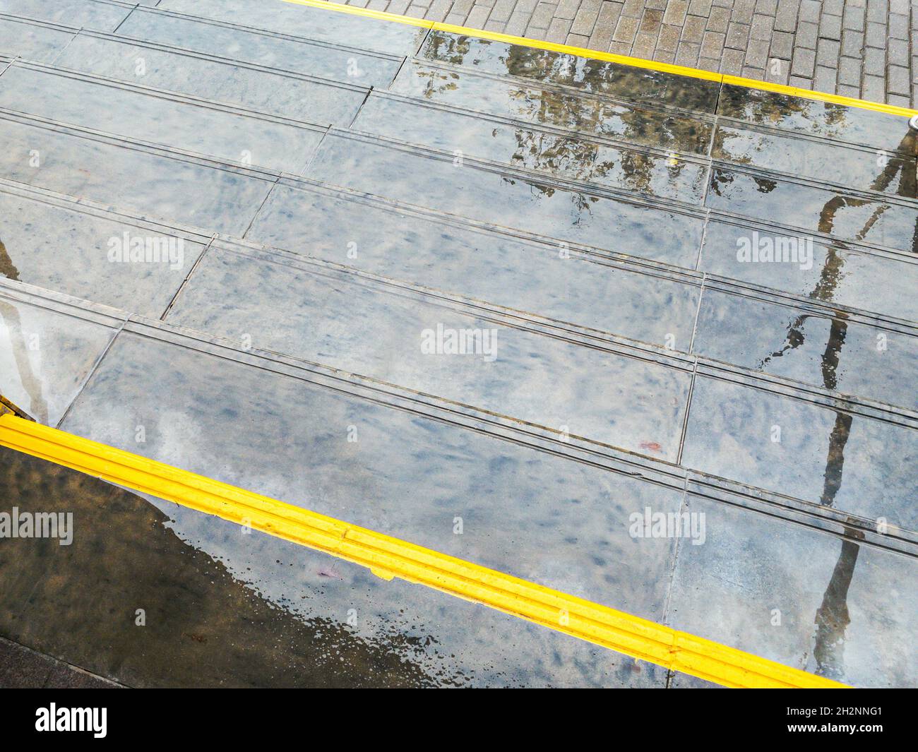 scale di granito bagnate con nastro di avvertimento giallo. giorno piovoso in città. edificio pubblico urbano. Foto Stock