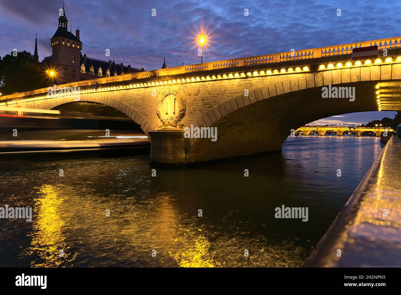PARIGI, FRANCIA - 01 ottobre 2019: Una vista mozzafiato del Ponte Pont au Change a Parigi di notte, Francia. Una nave da crociera in movimento sfocata Foto Stock
