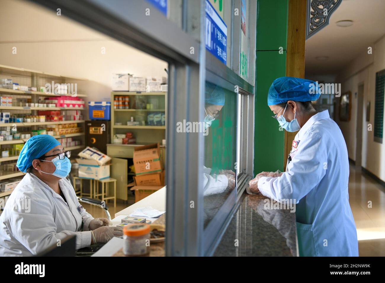 (211023) -- EJINA BANNER, 23 ottobre 2021 (Xinhua) -- un operatore medico attende di ottenere la medicina in una farmacia di un ospedale in Ejina Banner of Alxa League, North China's Inner Mongolia Autonomous Region, 22 ottobre 2021. Ejina Banner venerdì ha iniziato a fornire un pasto gratuito ogni giorno per i turisti bloccati in hotel a causa della prevenzione e controllo COVID-19. A questi turisti è stato inoltre fornito un servizio di consegna gratuito di medicinali e di forniture per la prevenzione delle epidemie. (Xinhua/bei HE) Foto Stock