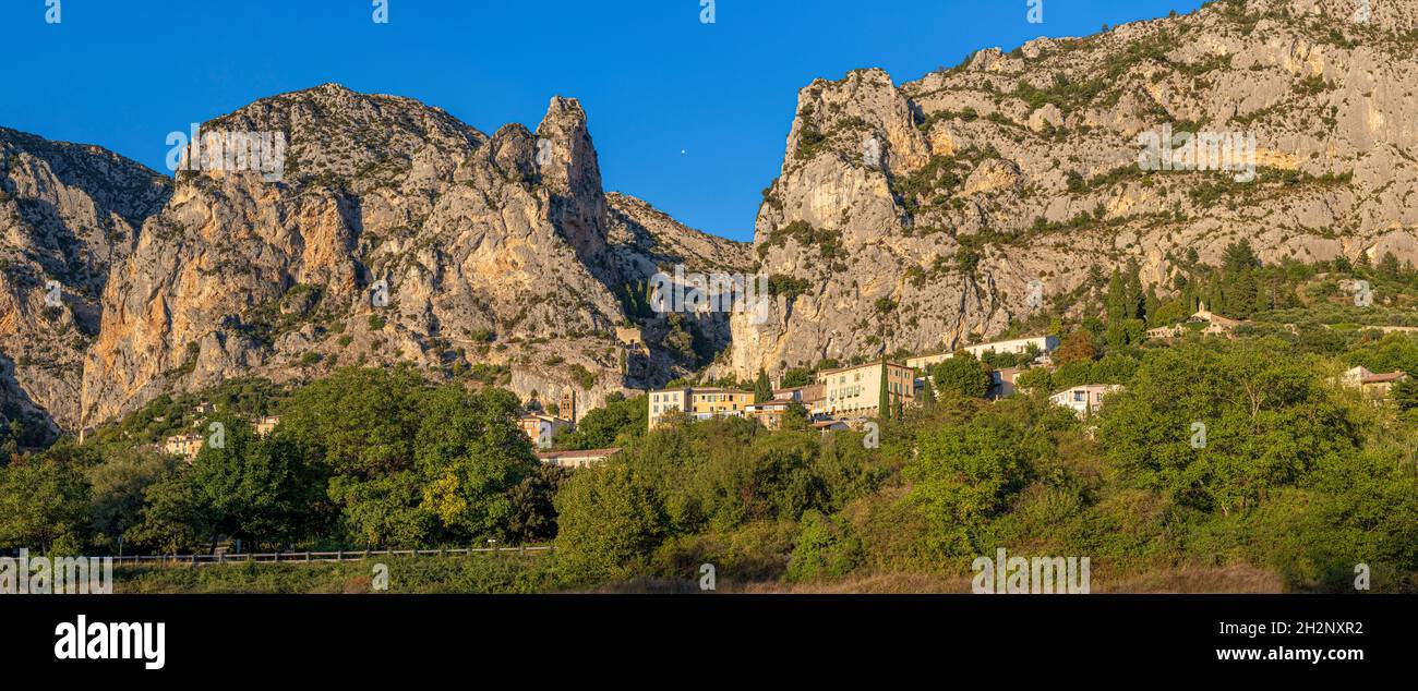 Panorama del delizioso borgo medievale di Moustiers Sainte Marie, Alpes Core d' Azur, Francia essendo bagnata in un bagliore dorato dal tramonto Foto Stock