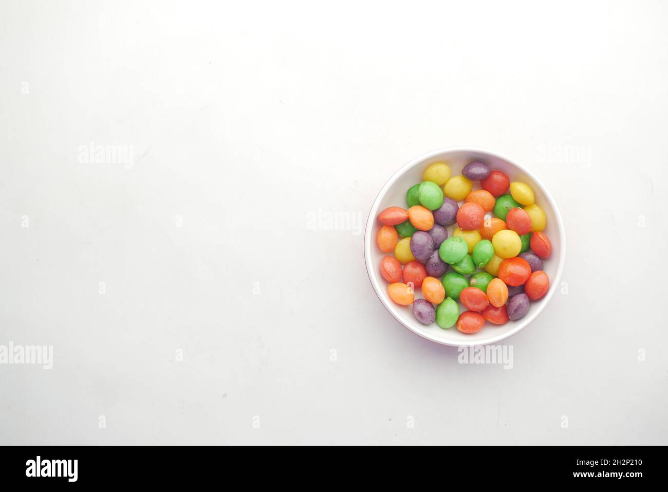 caramelle dolci multicolore in una ciotola su sfondo bianco Foto Stock